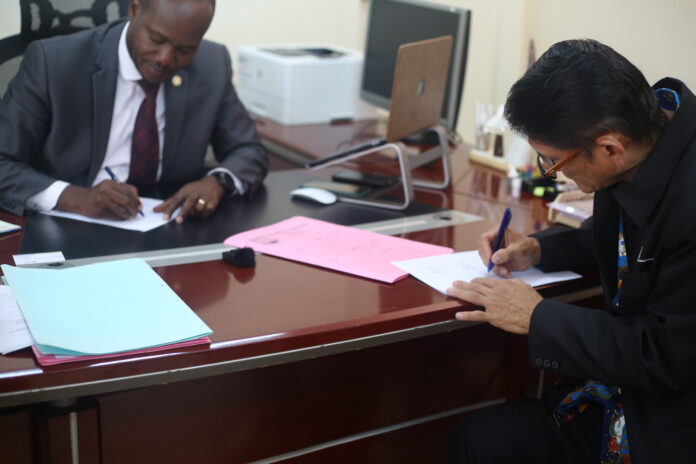Prof. Jude Lubega (L) and Dr. Hidayat Yorianta (R) Putting pen to paper.