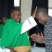 Rev. Fr. Kiibi while blessing the Dean School of Commercial Industrial Art and Design, Mr. Charles Kagwa Lwanga.