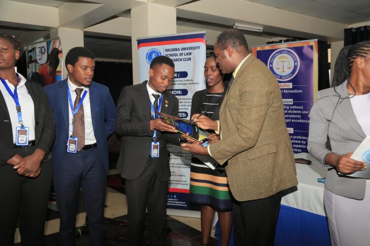 Outgoing Research President, Mwanje Gideon hands over Research paper to the Academic Registrar