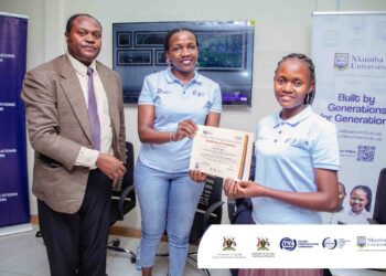 Madam Carolyn Vuni, Manager Technical Monitoring at UCC (M) Awarding a certificate of Participation to one of the Participants alongside Dr. Frank Pio Kiyingi (L).